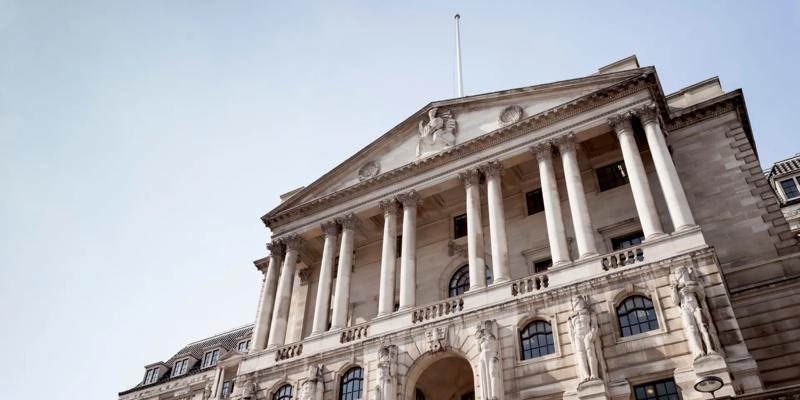 A historic stone building with tall columns and classical architecture under a clear sky. The structure represents a central bank or financial institution.