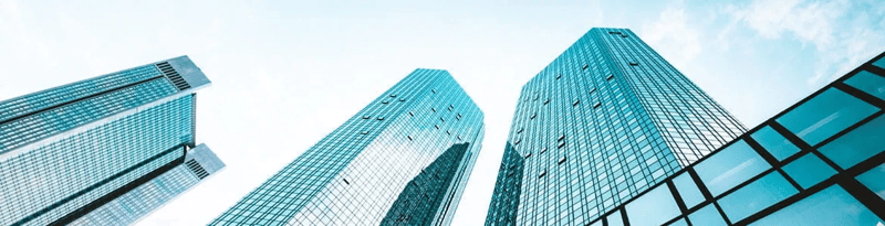Low-angle view of modern glass office buildings reaching toward the sky in an urban business district