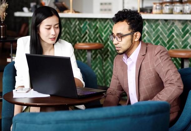 Two professionals discussing financial strategy on a laptop in a modern workspace representing FOREX.com collaboration and analysis