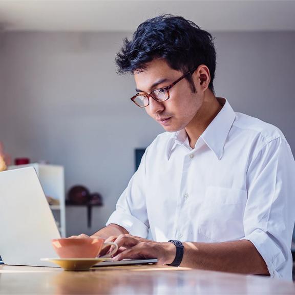 FOREX.com VIP Client typing on laptop with teacup