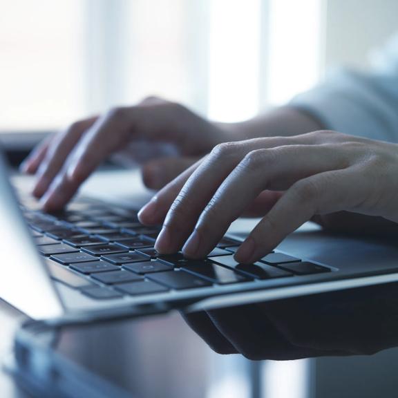 Close-up of hands typing on laptop keyboard