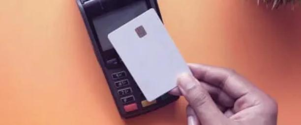 Fingers holding blank white credit card to a card reader