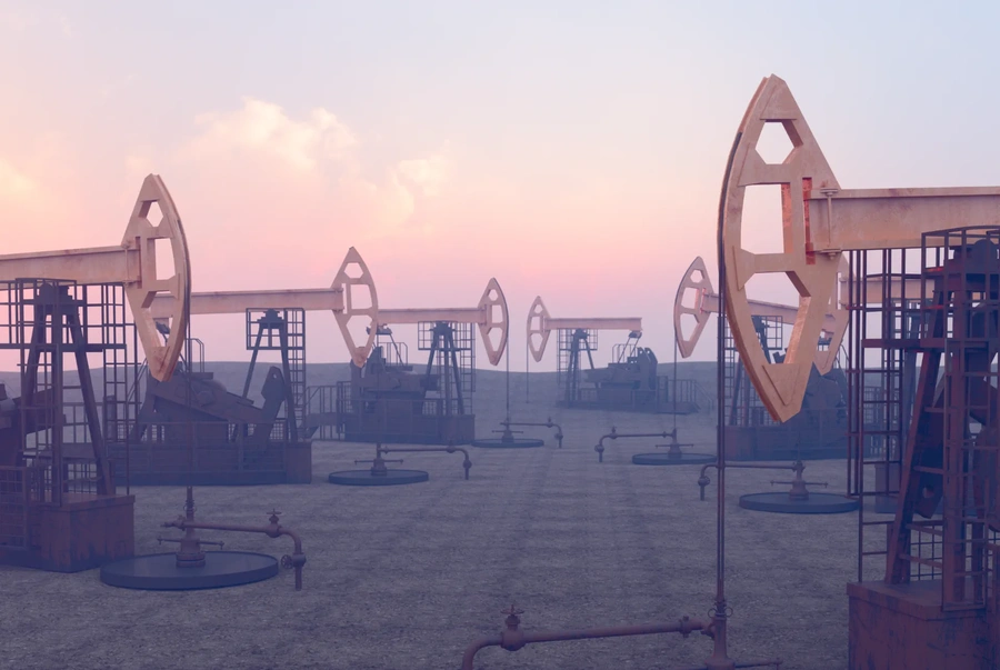 Image of several oil pump jacks operating in a field under a pink and blue sunset sky.