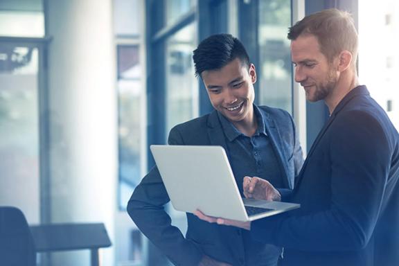 Two professional men looking at a laptop in a modern office environment