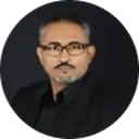 Portrait of a person wearing a black collared shirt against a dark background