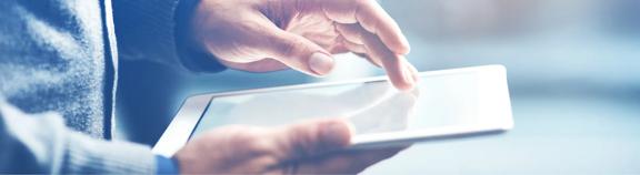 Close-up of hands using a digital tablet with a bright screen. The image represents modern technology and touch-based interaction.