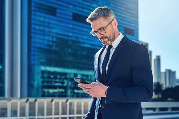 Professional businessman in suit using smartphone in modern city financial district