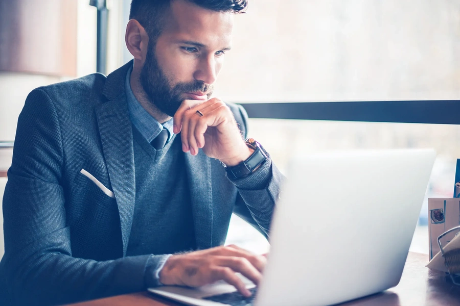 Professional man in business attire using a laptop at a desk