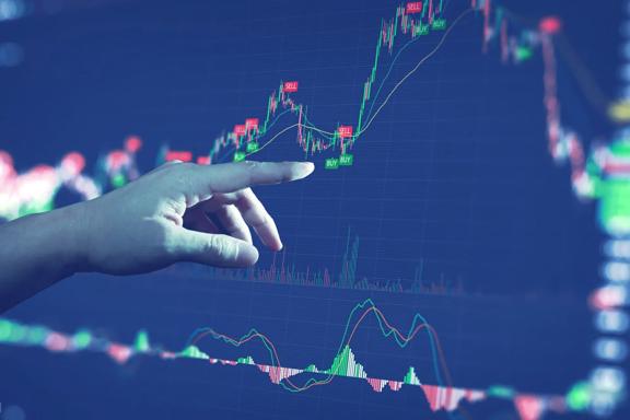 Hand pointing at financial chart on large screen