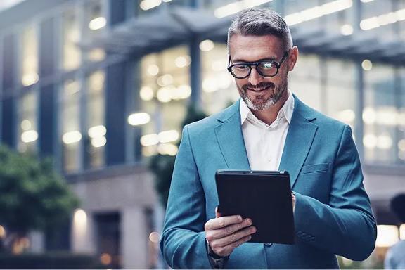 Professional man in suit holding tablet outside office building 