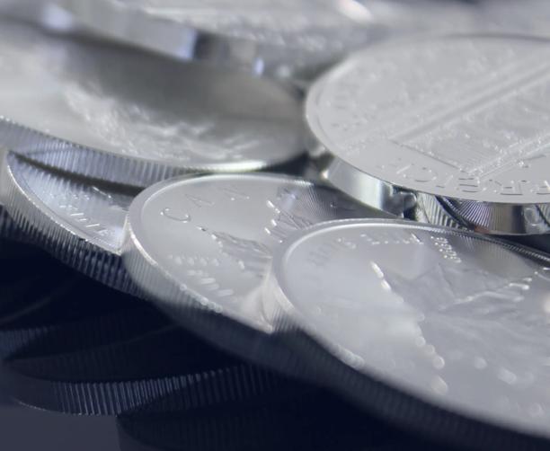 Close-up of stacked silver coins with detailed engravings and ridged edges