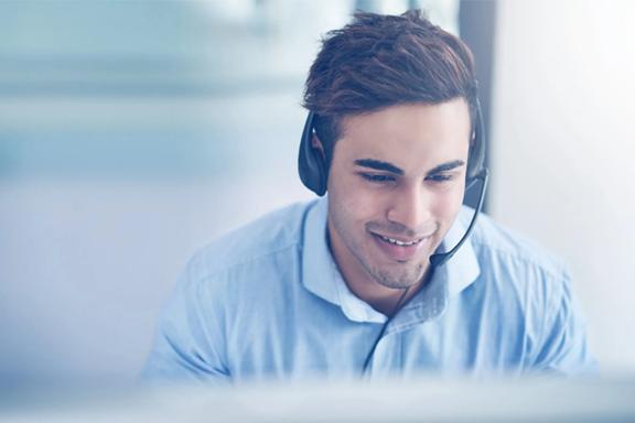 Individual wearing a headset and working at a computer in a professional office environment.