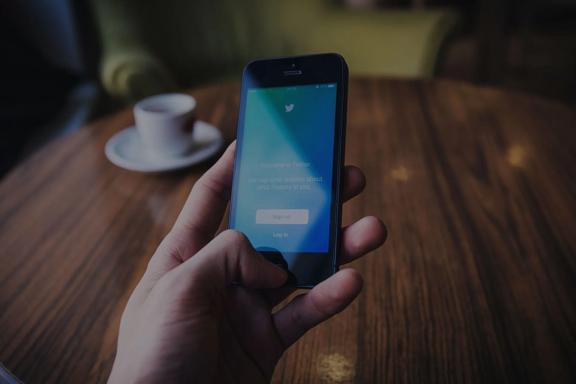 Hand holding mobile phone showing Twitter login screen